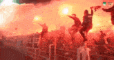 a crowd of people are holding flares in a stadium with a sign that says ' ao ' on it