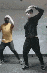 two men wearing face masks are dancing in a room
