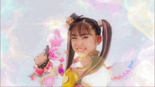 a young girl with pigtails is holding a pink toy