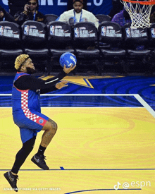 a man holding a basketball on a basketball court with nba chairs behind him