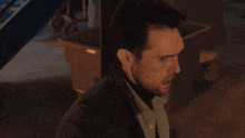 a man with a green light behind him looks at the camera