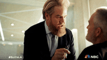 a man with a beard is talking to another man with the nbc logo in the corner