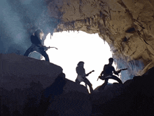 three people playing guitars in a cave with smoke coming out of it