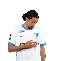 a man wearing a white ma cgm shirt holds his hand to his chest
