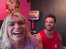 a man and a woman are laughing in a room with a balloon that says rude on it .