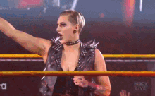 a woman is standing in a wrestling ring holding a microphone .