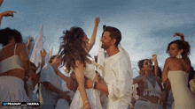 a man and a woman are dancing in front of a group of people and the words pranay varma are on the bottom right