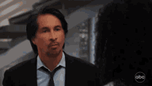 a man in a suit and tie is talking to a woman with abc written on the bottom
