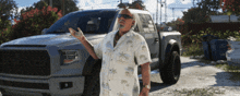 a man in a hawaiian shirt is standing in front of a ford truck