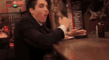 a man in a suit is sitting at a table with a measuring device on it .