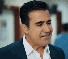 a man in a suit and white shirt is smiling and looking at the camera