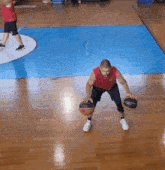 a man in a red tank top is dribbling a basketball on a basketball court