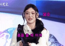 a girl wearing glasses holds a gun in front of a sign that says ek on it