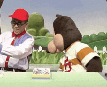 a man and a stuffed animal are sitting at a table with a box of crayons on the table