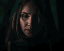 a close up of a woman 's face in the dark with a green background