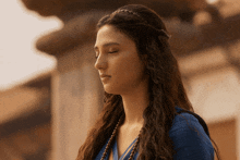 a woman with her eyes closed wearing a blue top