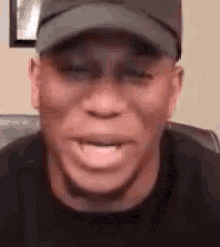 a man wearing a hat and a black shirt is smiling and looking at the camera .