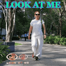 a woman is walking down a sidewalk with the words " look at me " above her
