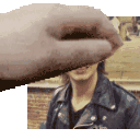 a person 's hand is covering a man 's face in a pixelated image .