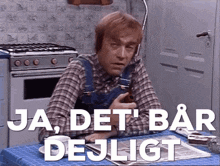 a man in plaid overalls sits at a table with the words ja det bar dejligt written above him