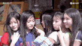 a group of young girls are posing for a picture with behind it written on the bottom right