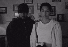 a man and a woman are standing next to each other in a room with pictures on the wall