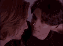 a man and a woman are looking at each other in a dark room