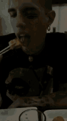 a man in a black shirt is drinking from a glass with straws