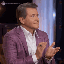 a man in a purple suit applauds with the hashtag #cbcdragonsden