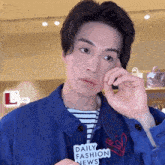 a man wearing a blue jacket has a daily fashion news sticker on his chest