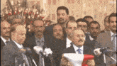 a group of men are standing in front of microphones and one of them is holding a flag .