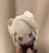 a person is holding a stuffed animal that looks like a girl with blue eyes .