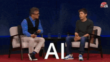 two men are sitting in chairs and the word ai is on the screen behind them