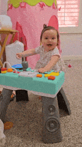 a baby girl is sitting on a toy table in a play room .