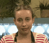 a woman in a striped shirt is looking at the camera .