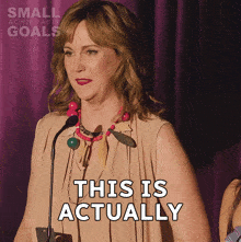 a woman speaking into a microphone with the words this is actually behind her