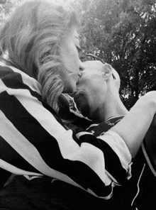 a black and white photo of a couple kissing