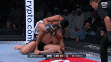 two men are wrestling in a boxing ring with a crypto.com banner in the background