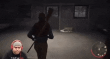 a man wearing headphones is playing a video game with a man holding a rifle in the background