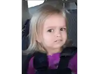 a little girl is sitting in a car seat and making a face .