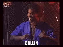 a man in a blue jacket is behind a chain link fence and the word ballin is on the bottom