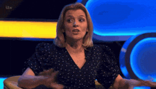 a woman in a polka dot shirt is sitting in a chair with her hands outstretched
