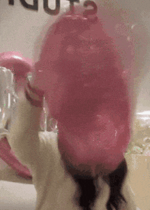 a girl is blowing up a pink balloon in front of her face .