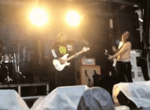 a man playing a guitar with a shirt that says god on it
