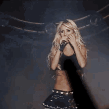 a blonde woman is singing into a microphone on stage