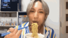 a man is eating ramen with chopsticks from a bowl .
