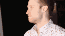 a man with a beard is wearing a white shirt with a floral pattern .