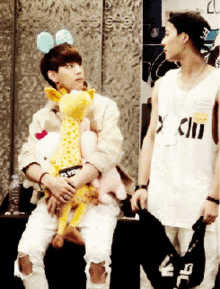 a man holding a stuffed giraffe and another man holding a hello kitty