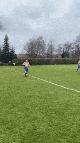a man in a blue shirt is holding a soccer ball on a soccer field