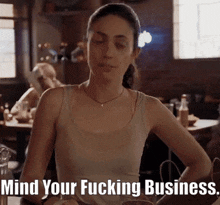 a woman sits at a table with her eyes closed and the words mind your fucking business below her